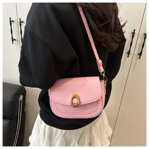 Gros plan du sac besace rose en cuir avec boucle fer à cheval dorée et bandoulière réglable
