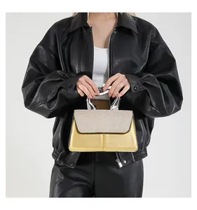 Chic gold crossbody bag with unique silver metallic handle shown with a black leather jacket