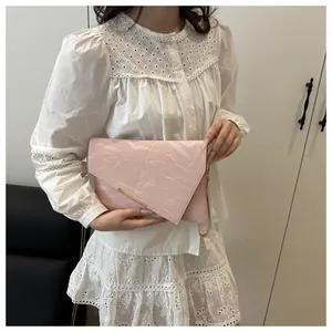 Close-up of pink envelope clutch bag featuring pleated texture and elegant metal hardware