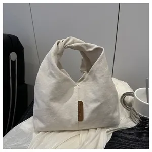 Vue détaillée de la poignée nouée et de l'étiquette en cuir sur le cabas en toile blanc cassé