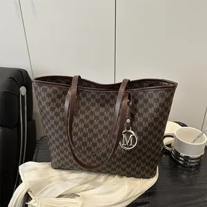Brown monogram tote bag with large capacity and leather handles on wooden tabletop