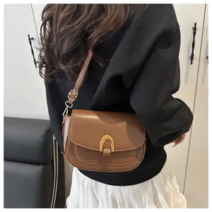 Détail du sac besace caramel avec fermoir doré en U et bandoulière réglable sur modèle