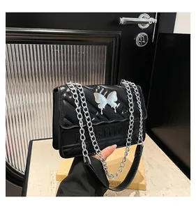 Detail of black quilted faux leather crossbody bag featuring silver butterfly metal buckle