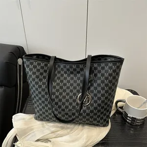Chic dark grey tote bag with monogram print and metal M charm on a black table