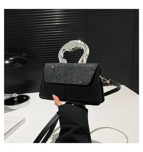 Detail of crossbody bag featuring rhinestone flap and fluid silver metal handle