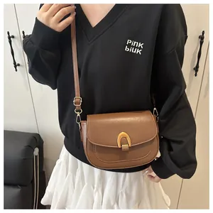 Détail d'un sac besace marron avec une boucle dorée en forme de fer à cheval