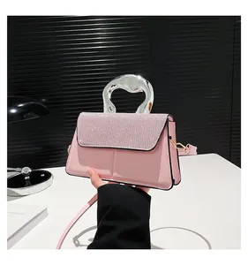 Detail of light pink crossbody bag with shimmering rhinestone lid and wave metal handle