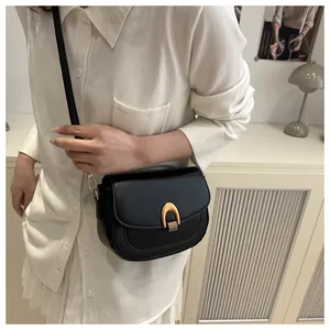 Détail d'un sac bandoulière vintage noir avec fermoir doré porté par un mannequin