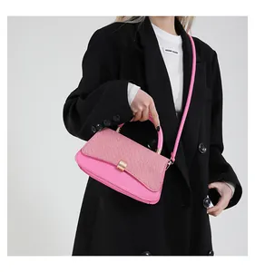 Rosafarbene Handtasche mit gewebter Klappe und goldener Schnalle an einem Model