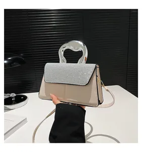 Detail of cream square bag with silver rhinestone flap and unique metal handle