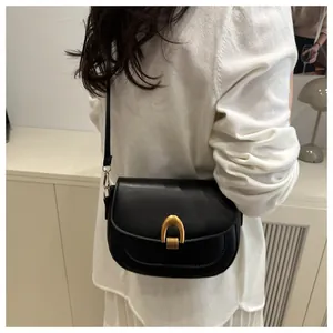 Gros plan d'un sac besace noir avec boucle métallique dorée en forme de fer à cheval