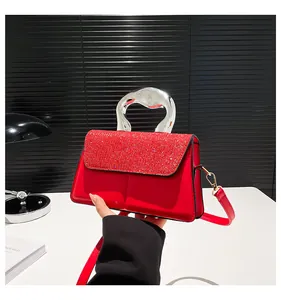 Close-up of red sequined handbag featuring a unique ergonomic silver metal handle