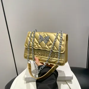 Golden quilted crossbody bag with metal chain strap and silver butterfly buckle
