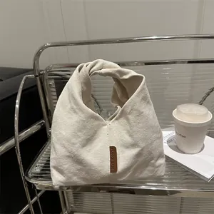 Sac fourre-tout minimaliste en velours côtelé beige avec étiquette en cuir sur étagère