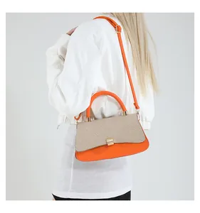 Detail einer hellorangen Leder- und beige gewebten Umhängetasche mit goldener Schnalle