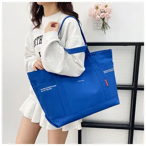 Detail of royal blue canvas tote bag showing multiple pockets and industrial typography