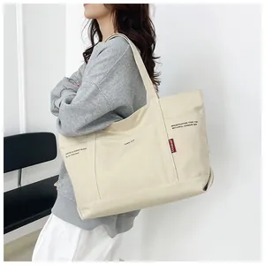 Detailed view of large canvas tote bag with black print and red woven brand tag