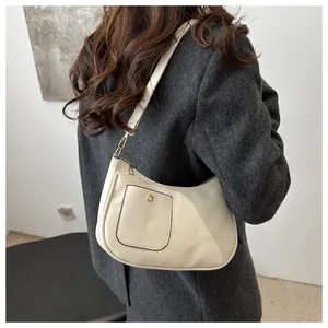 Detail view of a cream crescent shoulder bag featuring a gold buckle and textured leather
