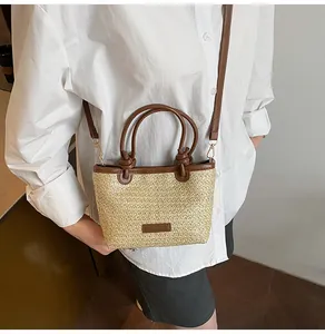 Détail du sac en paille tressée avec poignées en cuir marron et nœuds avec bandoulière