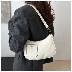 Detail of cream crescent shoulder bag with golden buckle and textured grey blazer