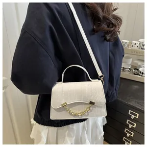 Detail of white crocodile pattern box bag with gold chain and top handle on a model