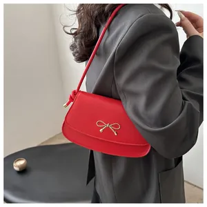 Detail of red saddle bag with gold bow clasp and knotted shoulder strap detail