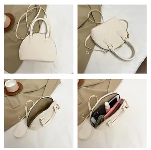 Detalle de bolso de concha crema con piel de cocodrilo y vista de su capacidad interior
