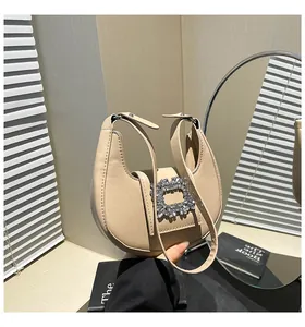 Detail of elegant beige crescent handbag featuring a luxury square rhinestone buckle