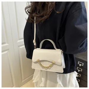 Detail of white crocodile pattern crossbody bag with gold chain trim and top handle