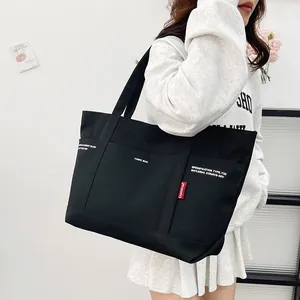 Minimalist black canvas tote bag with multi-pockets and stylish red label for daily commute