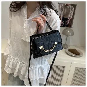 Close-up of black crocodile pattern leather handbag with gold chain and top handle strap