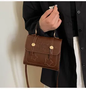 Detail shot of vintage brown leather bag with golden hardware and star embossed pattern