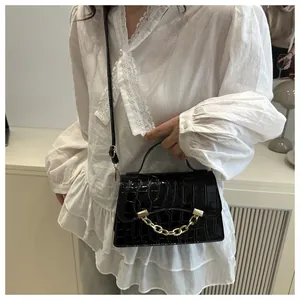 Detail of black crocodile embossed handbag with luxury gold chain and top handle