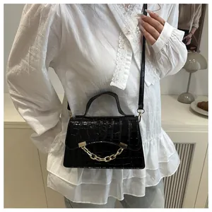 Fashionable black crocodile pattern box bag with gold chain strap on a white lace outfit