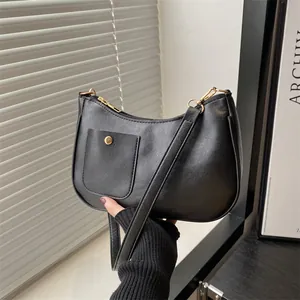 Minimalist black crescent shoulder bag with golden button detail in a handheld view