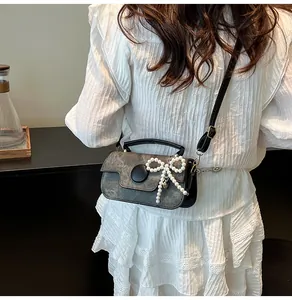 Detail of grey marble pattern crossbody bag with pearl bow charm and black strap