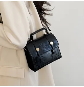 Close-up of black crossbody bag featuring star applique and gold-tone metal hardware
