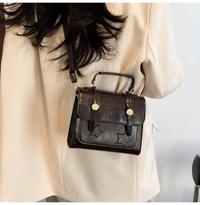 Detail view of vintage brown crossbody bag with star patches and embossed text