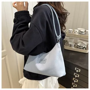 Détail du sac seau plissé bleu clair montrant les textures et l'étiquette de marque
