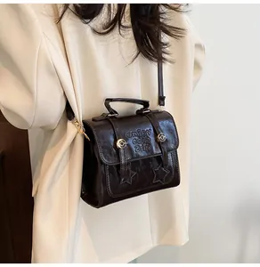 Detail of dark brown leather handbag featuring star embossing and gold hardware