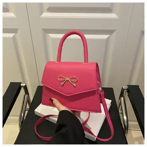 Detailaufnahme der pinken Mini-Handtasche mit goldenem Metall-Schleifenverschluss