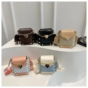 Detailed view of mini crossbody bags with M-letter prints and gold heart buckles
