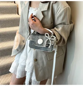 Detail shot of grey matte crossbody bag with white pearl bow and metallic heart charm