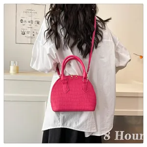 Detalle del bolso concha rosa con textura de cocodrilo y asas de mano superiores
