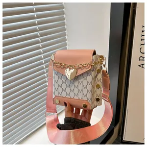 Détail du mini sac bandoulière rose avec fermoir cœur doré et motif à lettres M