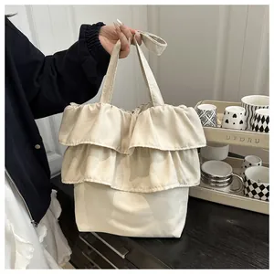Detail of ruffled tiered cream tote bag showing soft fabric texture and wide strap