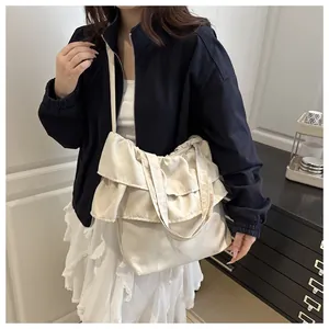 Detail of cream pleated layered canvas tote bag showing textured ruffles and shoulder strap