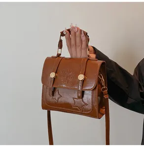 Detail of caramel PU leather handbag featuring embossed text and gold metal hardware