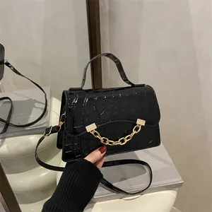 Fashionable black croc-embossed handbag with gold chain handle and detachable strap