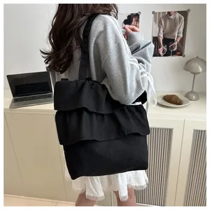 Detailed side view of black tiered ruffle canvas tote bag in a cozy lifestyle setting
